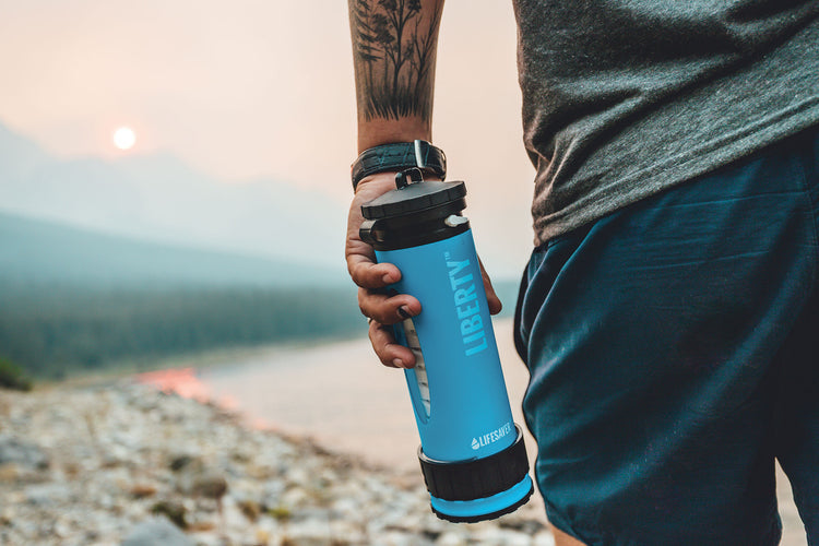A man on a lake shore holding a blue LifeSaver Liberty