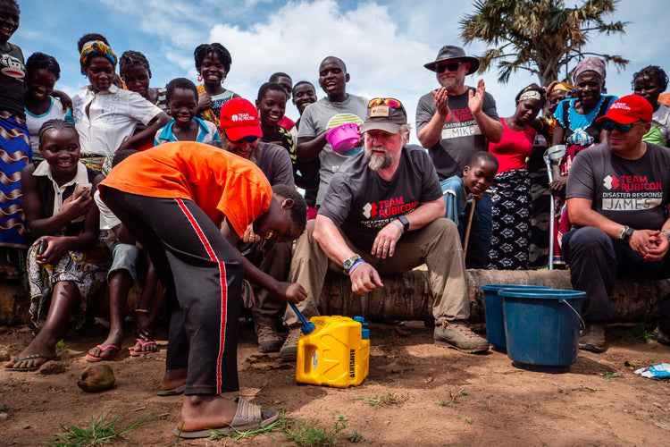Team Rubicon disaster response teaching villagers how to use a LifeSaver Cube to purify their water