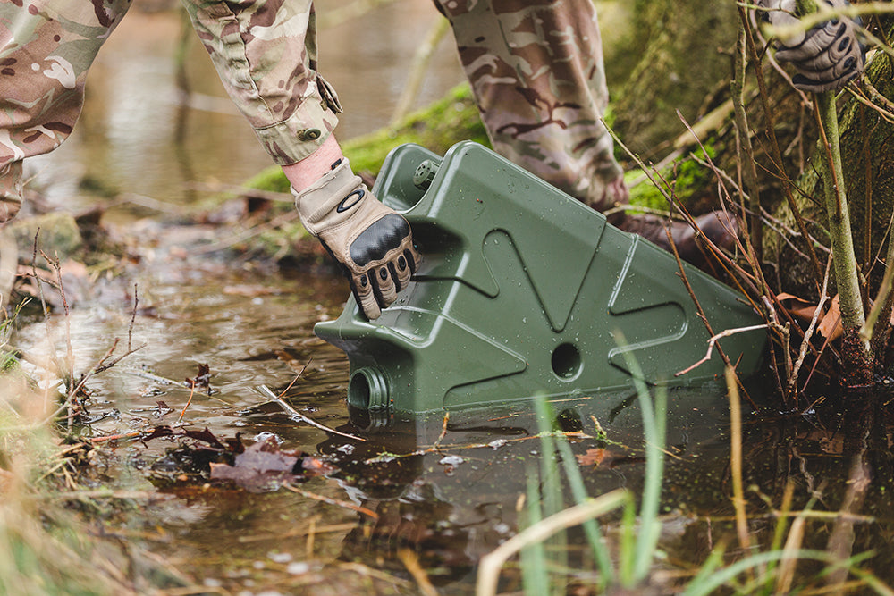 Soldier filling a green Jerrycan from a stream